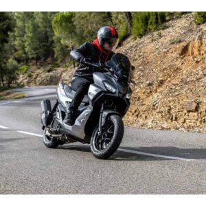 Ein Motorradfahrer fährt auf einer kurvenreichen Straße. Der Fahrer trägt eine schwarze Jacke und einen schwarzen Helm mit roten Akzenten.