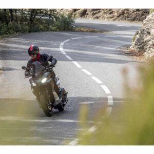 Ein Motorradfahrer auf einer kurvenreichen Straße. Der Fahrer trägt einen schwarzen Helm und eine schwarze Jacke.