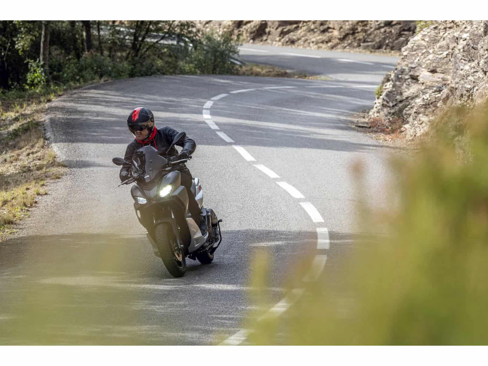 Ein Motorradfahrer auf einer kurvenreichen Straße. Der Fahrer trägt einen schwarzen Helm und eine schwarze Jacke.